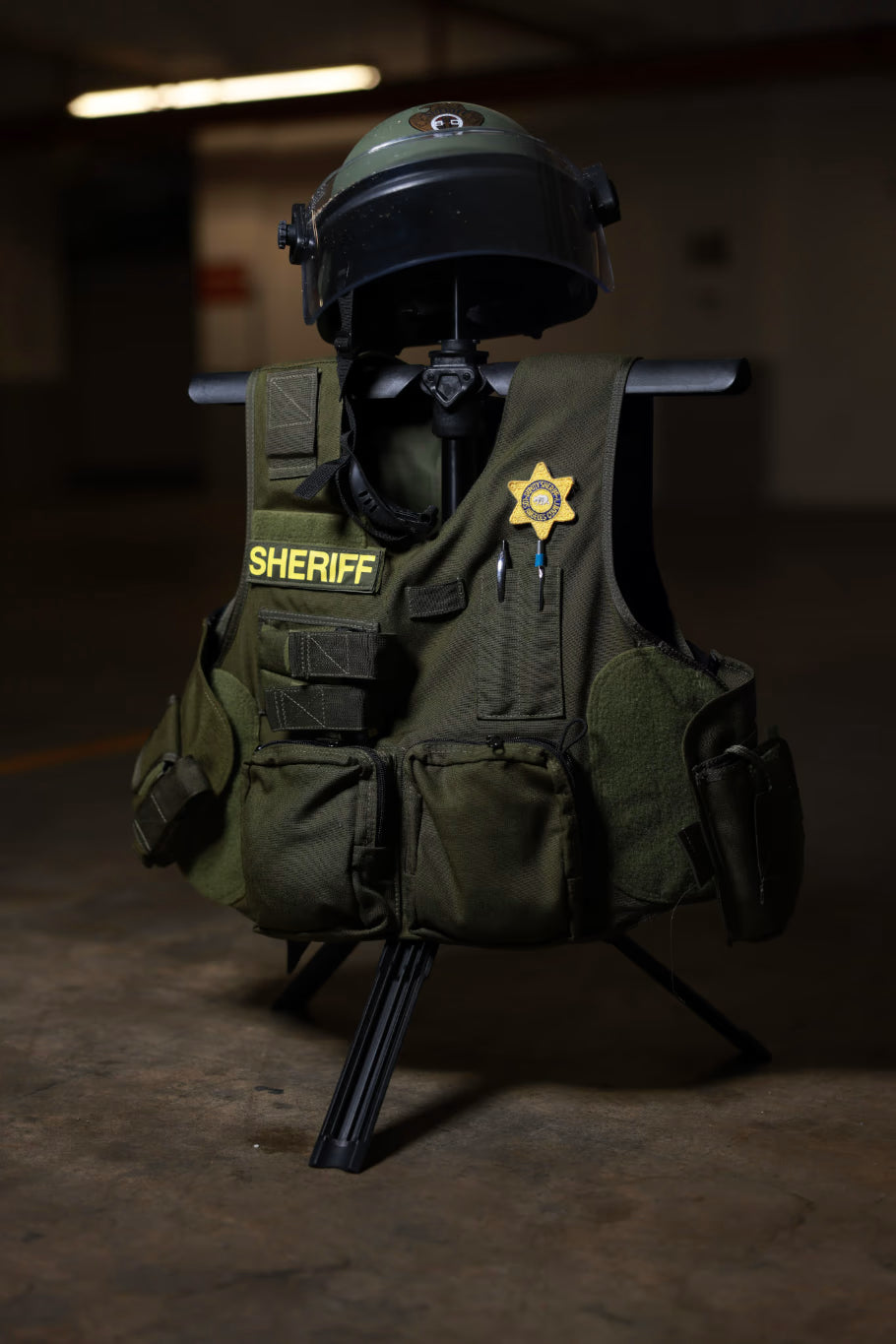 Green vest with 'Sheriff' and a star emblem along with a helmet on a Swift portable gearstand.
