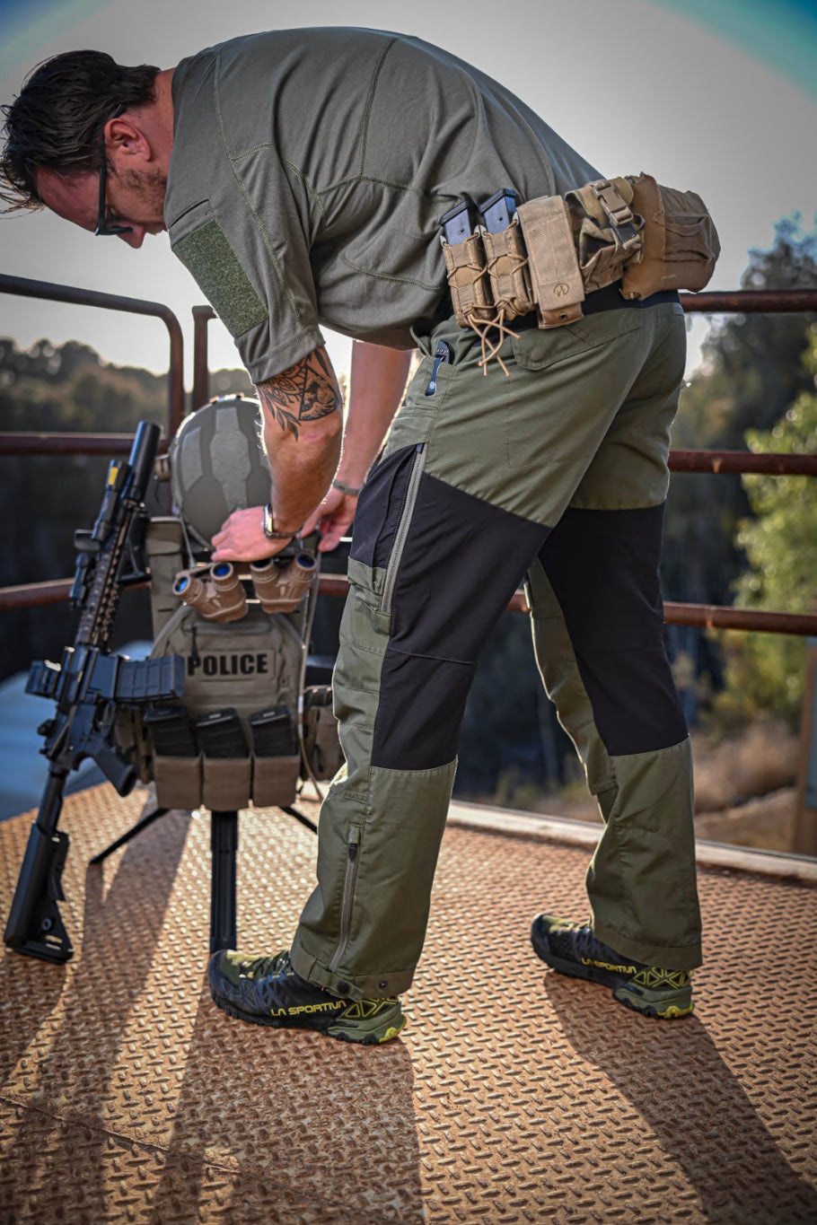 Man standing on a platform with sun setting in background. He is adjusting his armor and other gear on a Swift Portable Gearstand.
