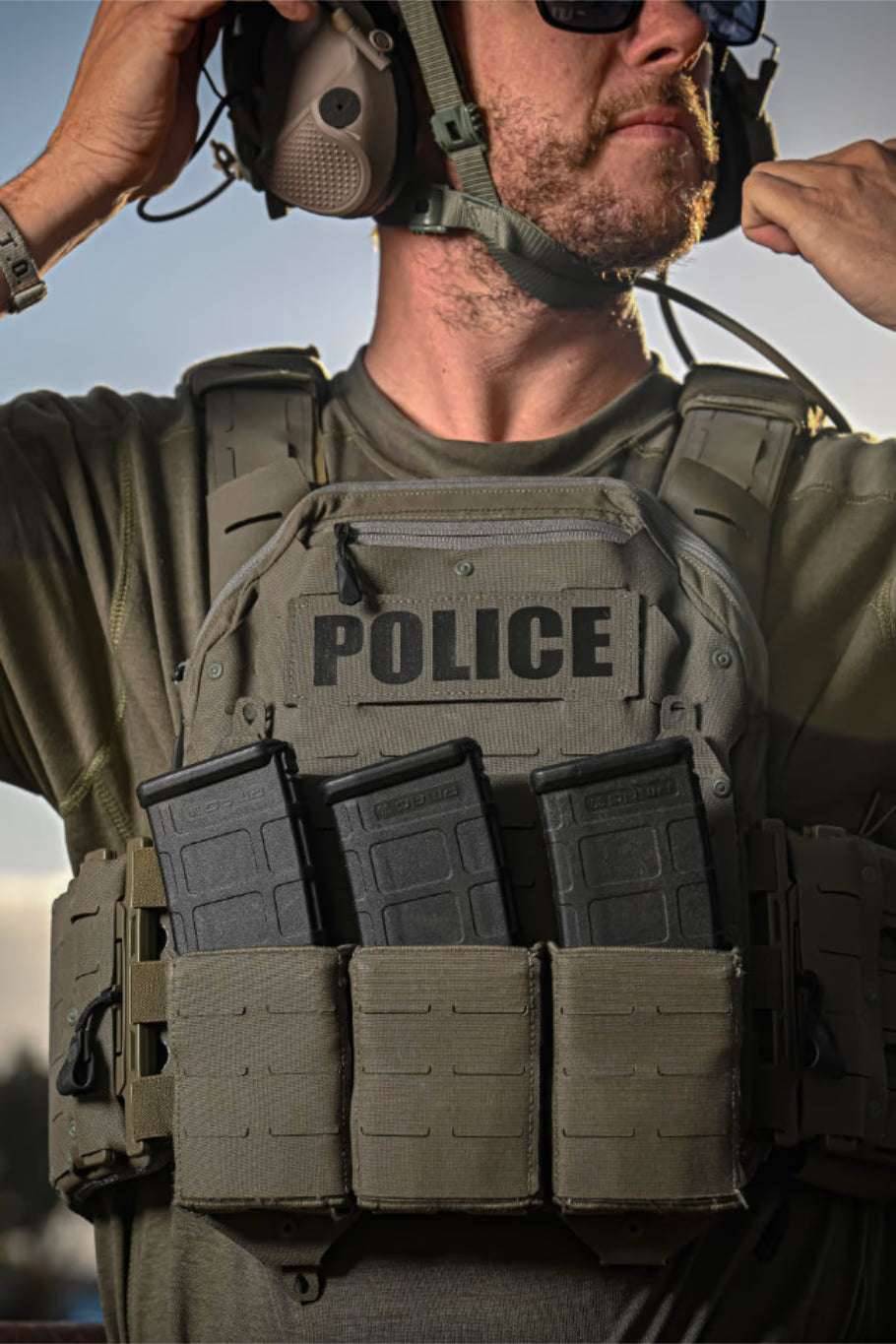 Our cofounder wearing body armor, helmet, and headset looking left with the Sun beginning to set in the background.